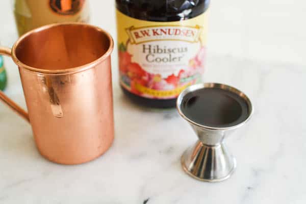 Close up of Hibiscus juice in a jigger on a marble cutting board.