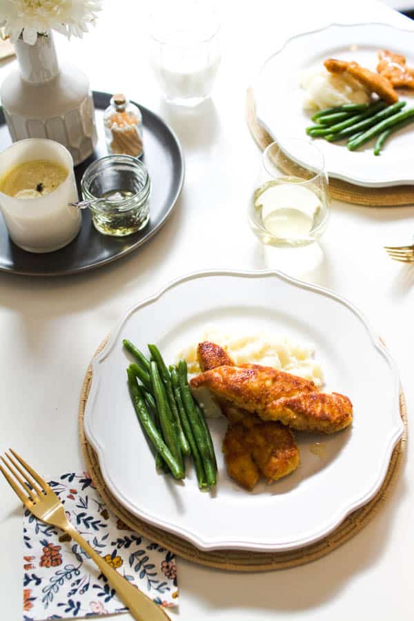 Truffle honey chicken served over mashed potatoes and a side of green beans on a dinner table.