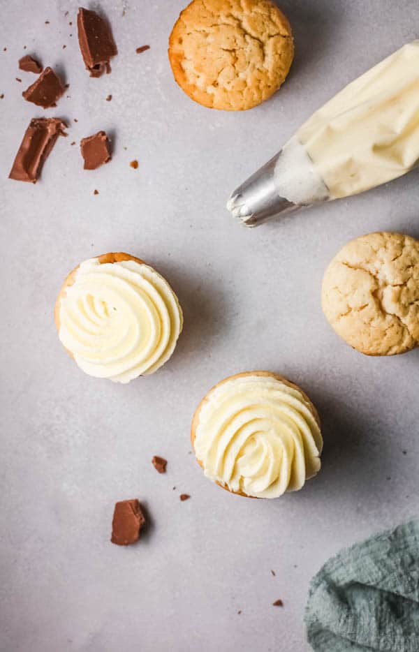 Easy white russian cupcakes from boxed cake mix on a table next to frosting in a piping bag.