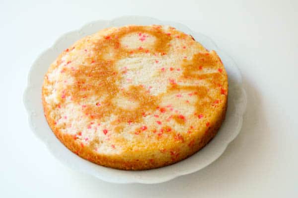 cherry chip cake unfrosted on a cake plate to be turned into a pinata cake with hard chocolate dome