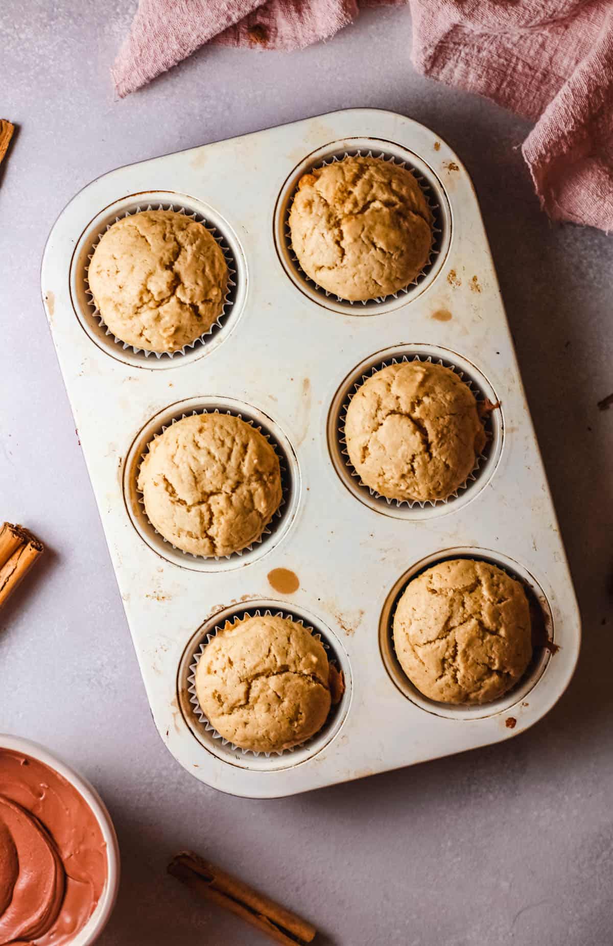 A cupcake pan holding baked cupcakes on a table.