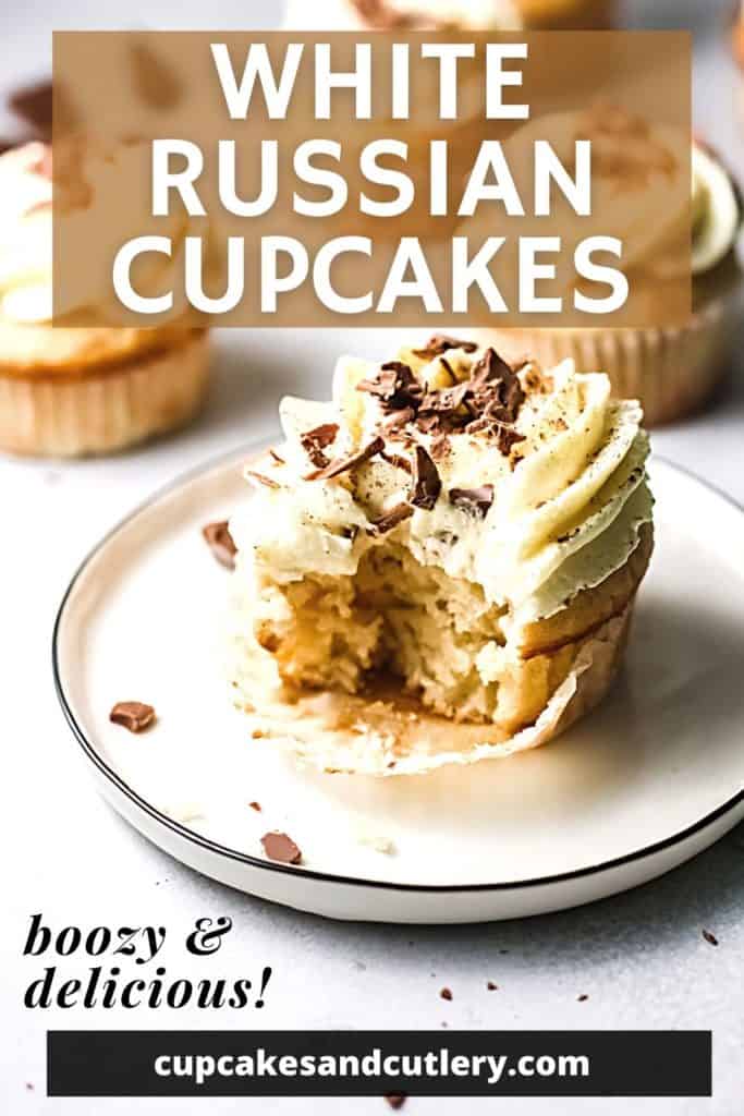 A White Russian Cupcake topped with Irish cream Frosting and chocolate shavings with a bite taken out of it on a white plate.