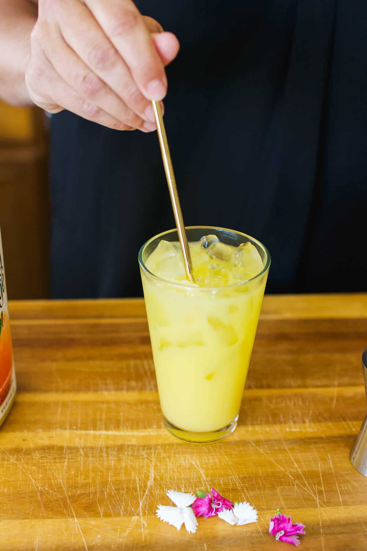 Woman stirring a cocktail with orange juice.