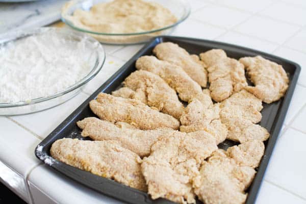 Homemade chicken tenders on a baking sheet on the counter.