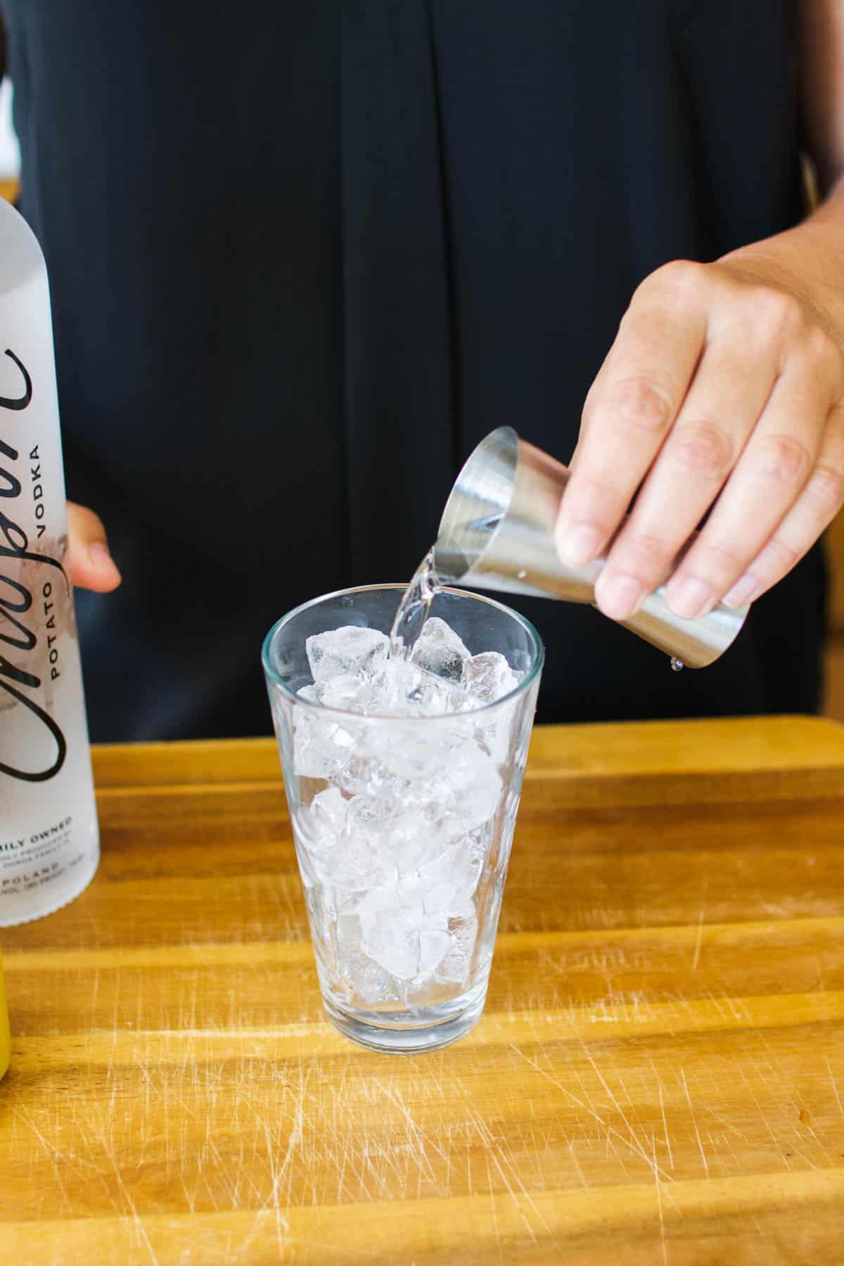 Woman adding vodka to a cocktail glass.