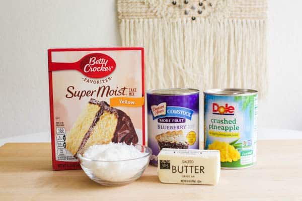 Ingredients for a pineapple blueberry dump cake on a cutting board.