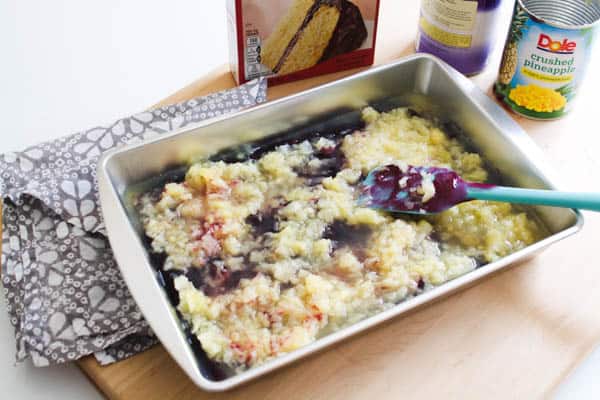 Baking dish with canned blueberry pie filling and crushed pineapple on top.