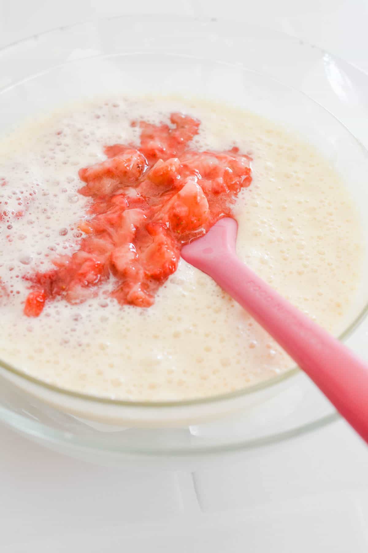 A bowl with creamy mixture and frozen strawberries.
