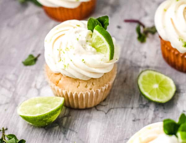 Frosted cupcake with a lime wedge and mint garnish.