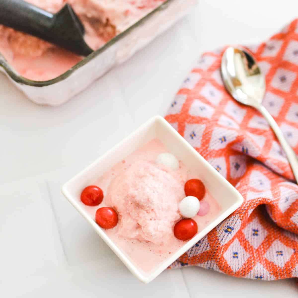 Strawberry frozen yogurt in glass bowl, ice cream balls, container