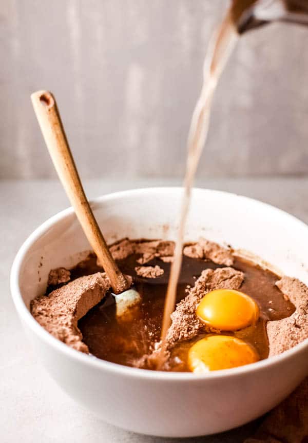 A bowl with eggs and cake mix and a spatula.