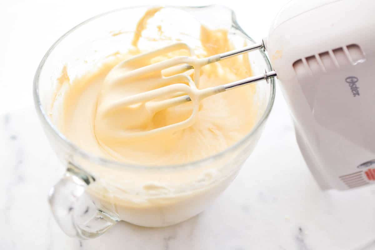 A glass bowl with cake batter and a hand mixer in the batter.