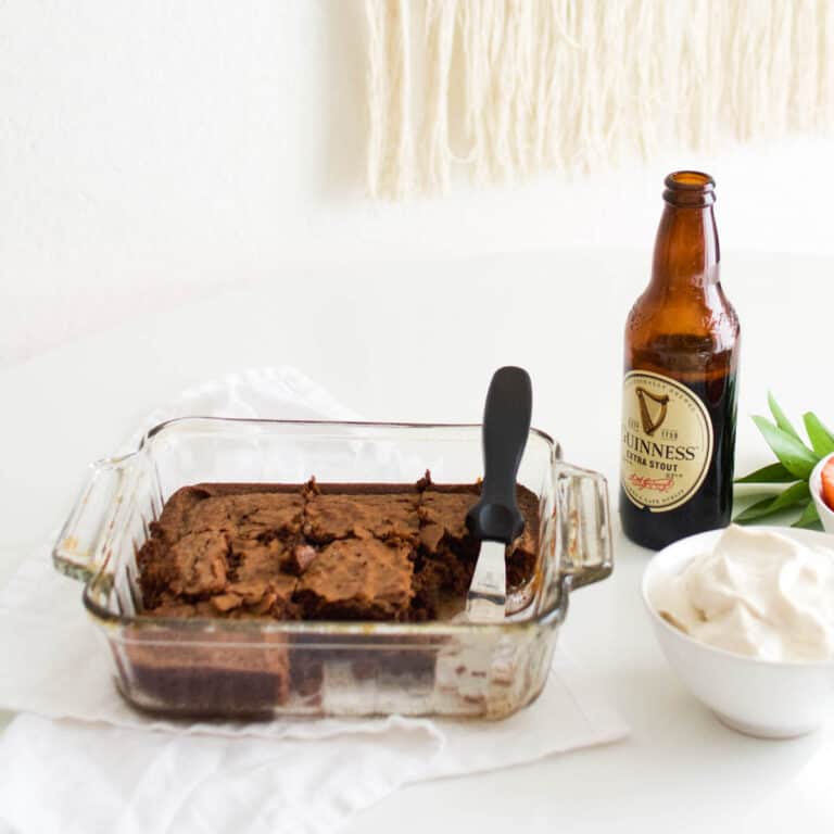 A pan of Stout Brownies on a table next to a bottle of Guinness.
