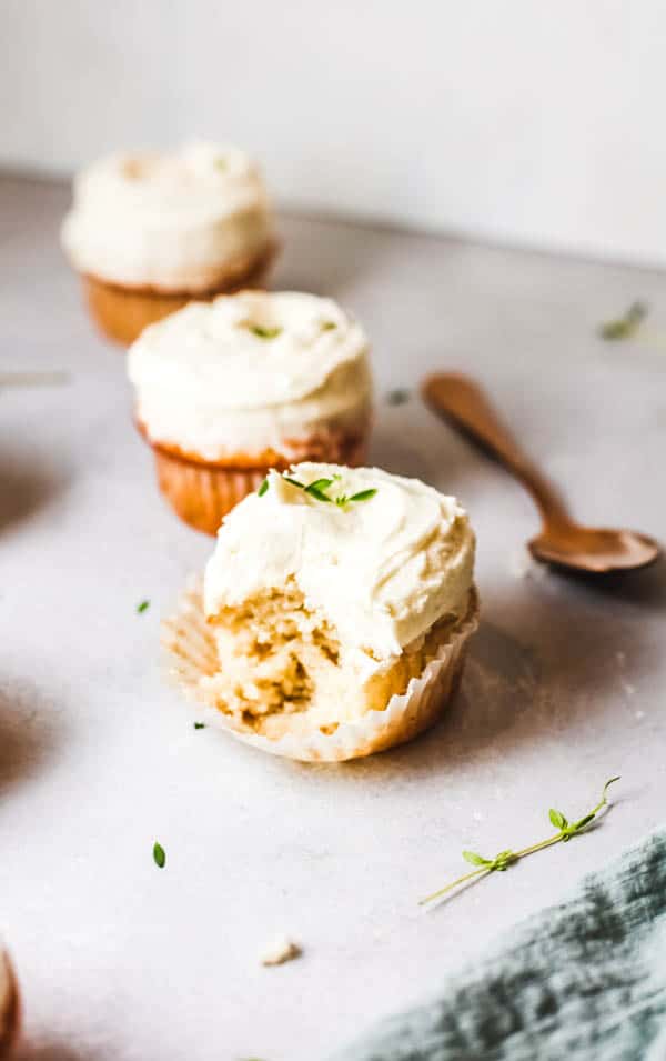 A few cupcakes on a table and the one in front has a bite out of it.