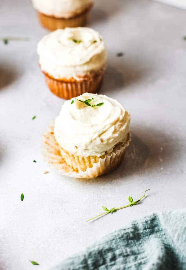 St. Germain cupcakes on a table topped with fresh thyme. 
