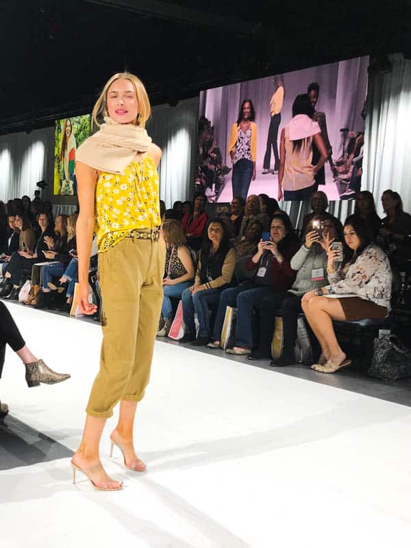 Woman in summer outfit with sweater tied in a unique way at her shoulders.