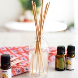 A DIY reed diffuser on a counter next to essential oils.