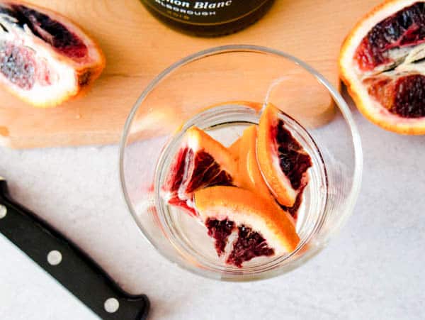 Pieces of fresh blood orange in the bottom of a wine glass.