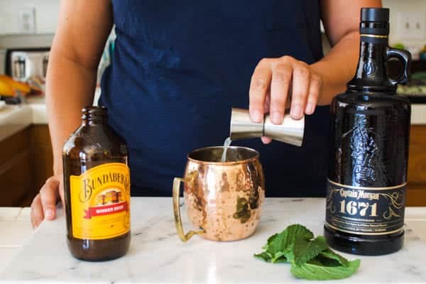 Woman adding lime juice to a copper Moscow Mule mug.