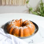 Close up of a bundt cake with powdered sugar on it on a table.