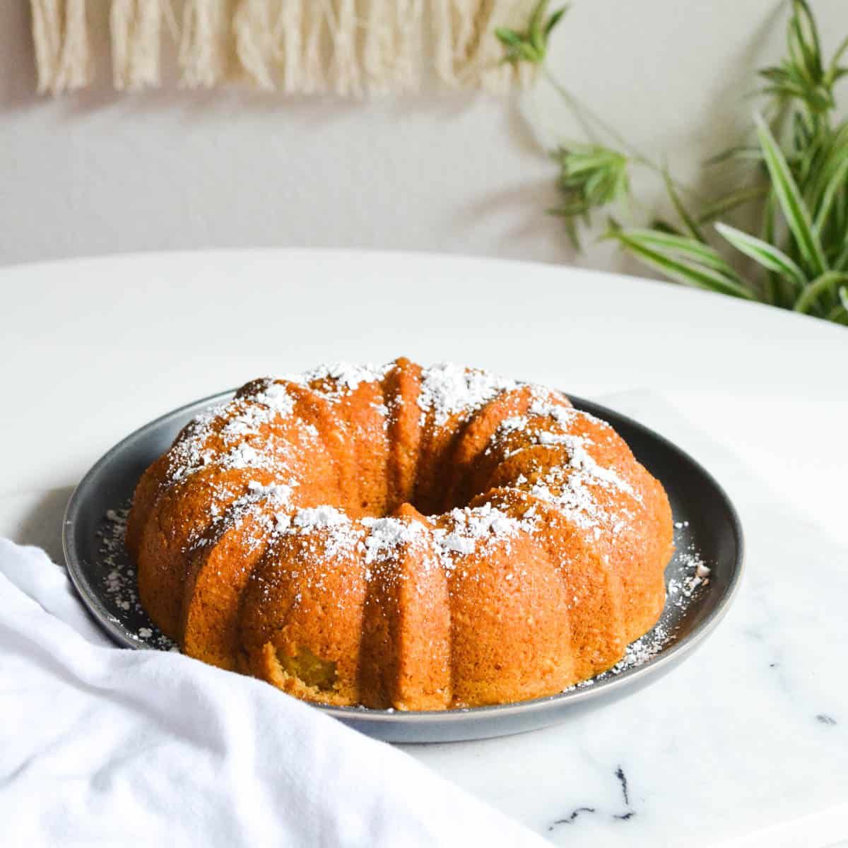 Close up of a bundt cake with powdered sugar on it on a table.