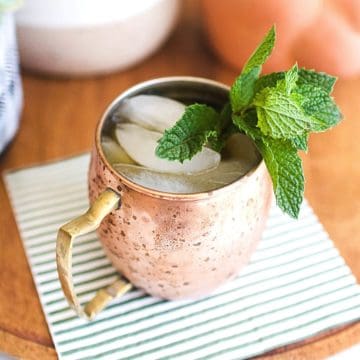 A copper mug with a Rum Moscow Mule cocktail topped with fresh mint.