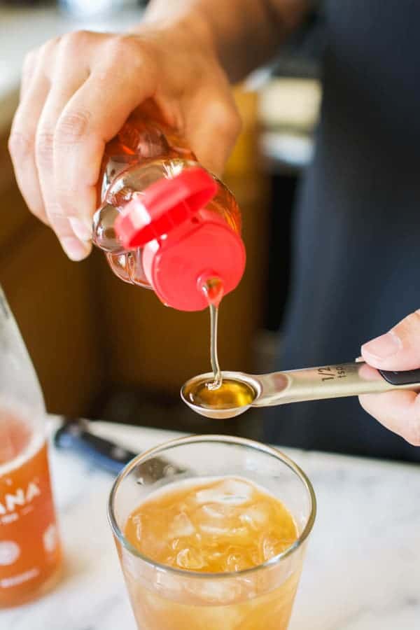 Woman measuring honey on a teaspoon.