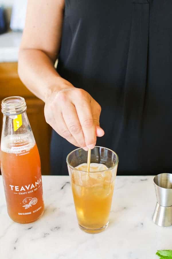 Woman stirring a glass of iced tea.