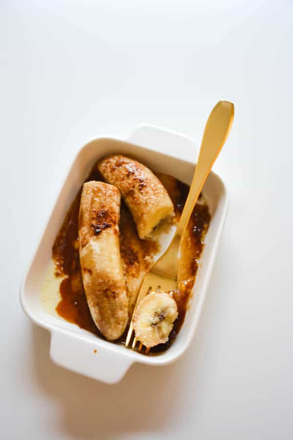 dish of oven roasted bananas with butter and brown sugar with a fork.