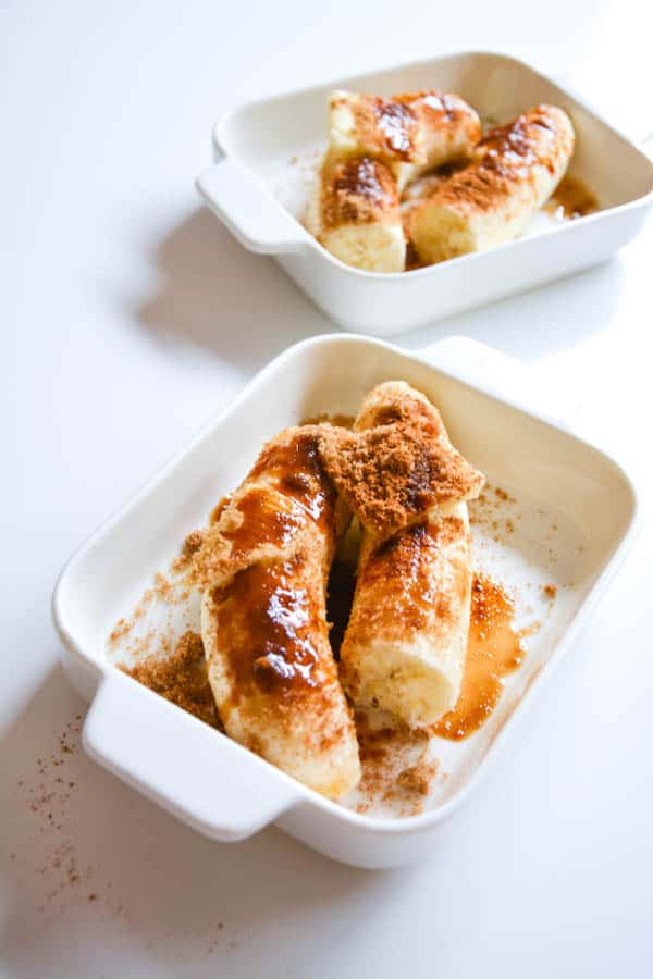 Bananas with brown sugar, cinnamon and butter in baking dishes.