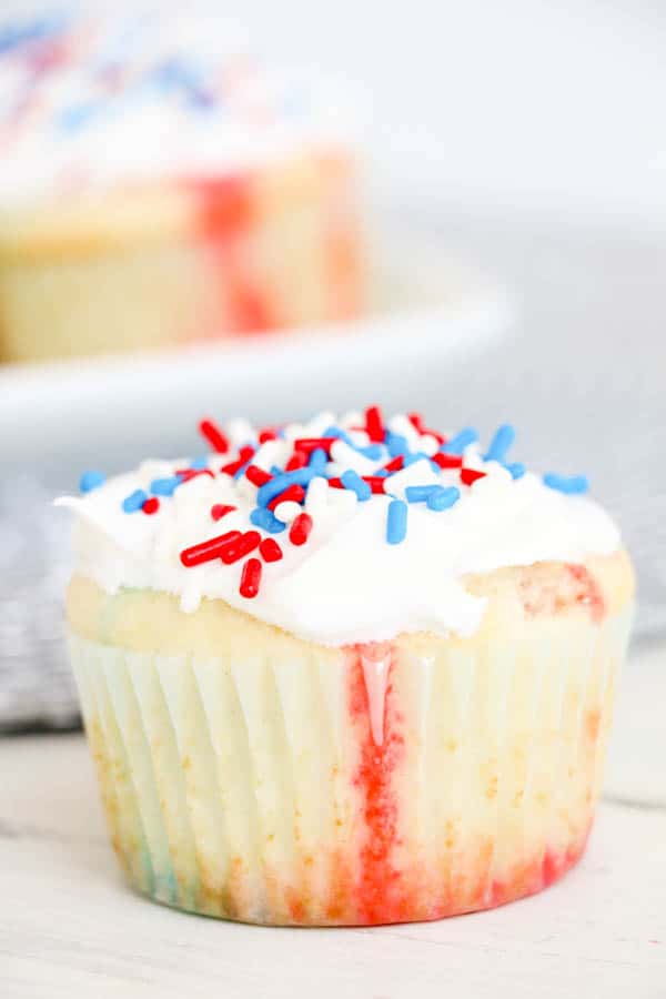 A patriotic cupcake on a table with red, white and blue sprinkles.