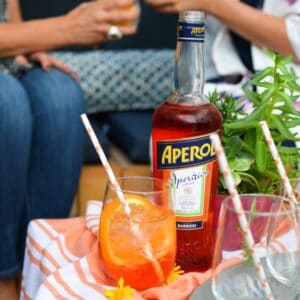 Close up of a glass with an Aperol Spritz cocktail next to a bottle of Aperol.