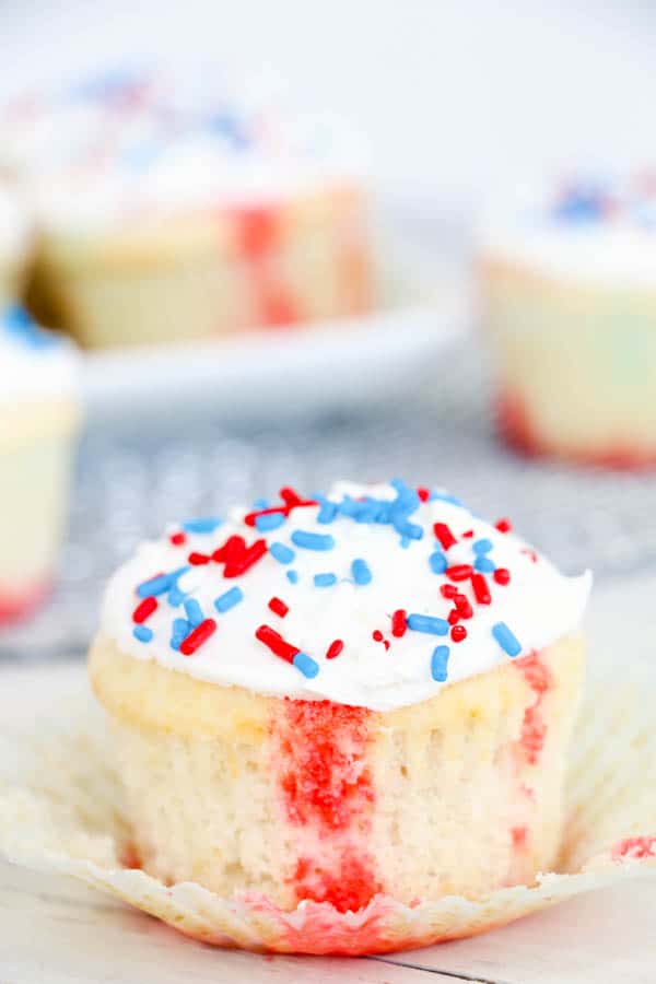 Cupcake sitting on a table with red, white and blue sprinkles on top and color through out the batter.