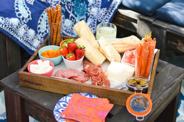 A snack board full of food on a picnic table.