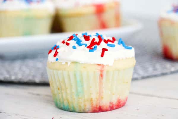 A red, white and blue Jello poke cupcake sitting on a table.