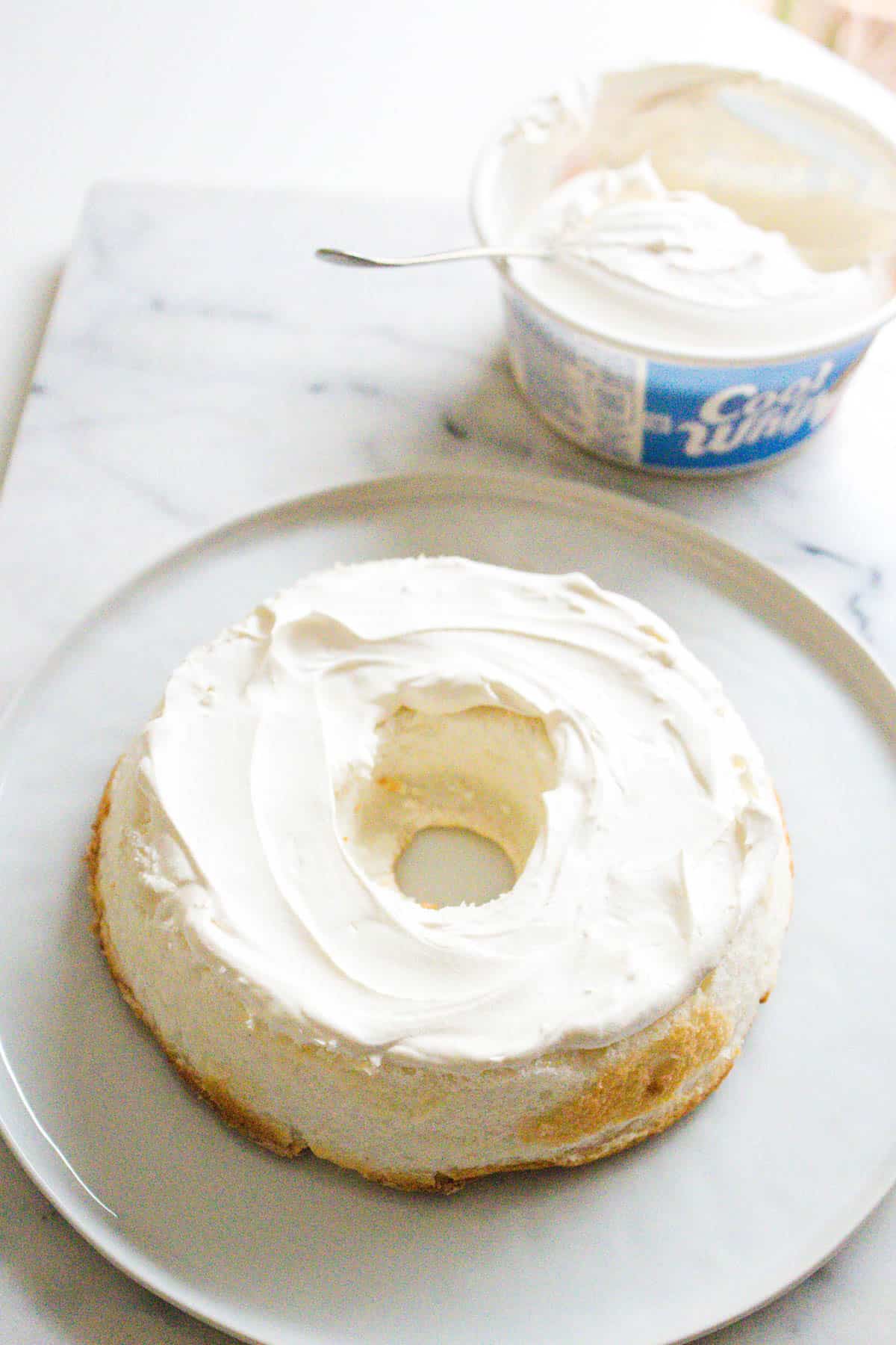 Sliced angel food cake with Cool Whip spread on and the container next to it.