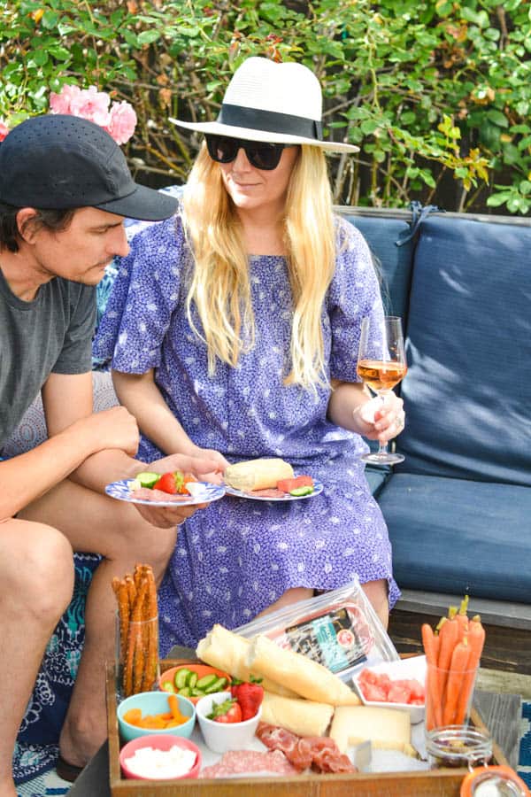 Husband and wife sitting on patio furniture enjoying a snack board.