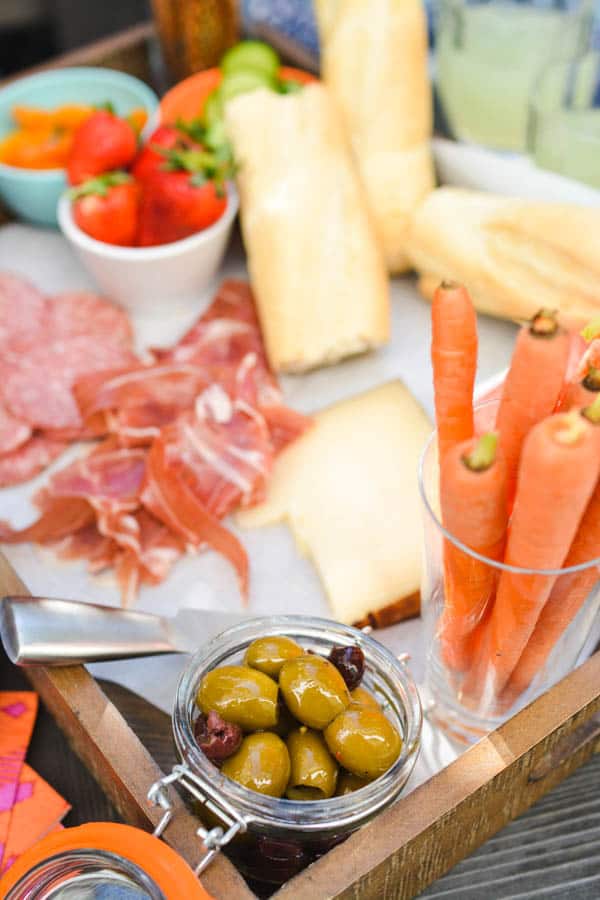 A tray of food on a table, with finger food and Prosciutto.