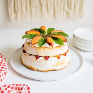Angel Food Cake with peaches in the middle of the layers and topped with peaches and fresh mint.