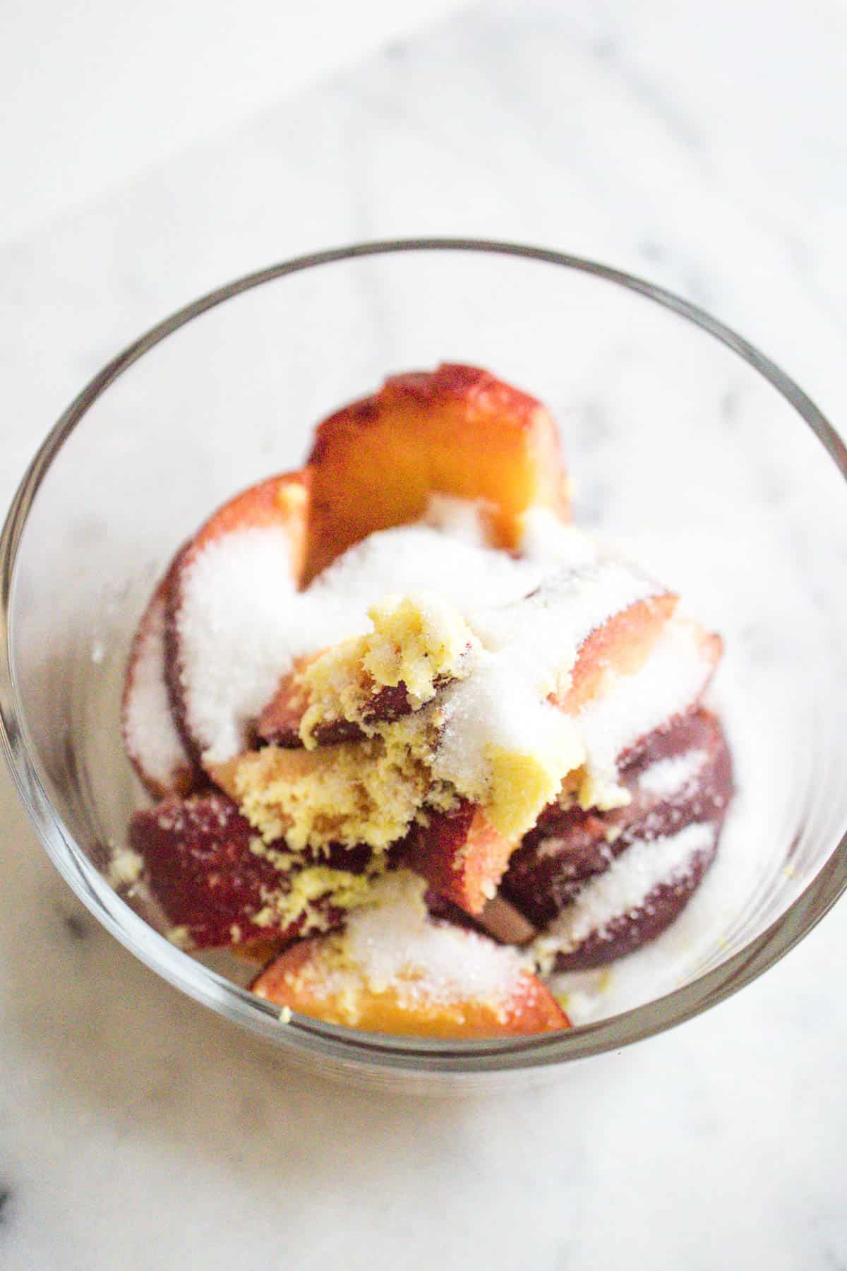 A bowl with macerated peaches, sugar and grated ginger.