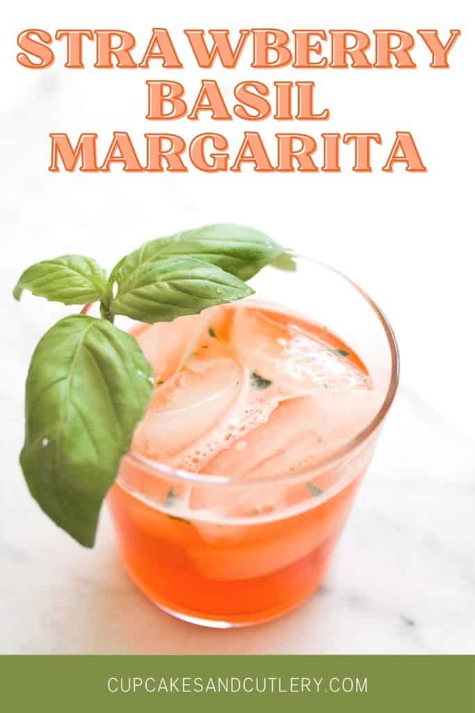 A basil garnished strawberry margarita on a table with text that says "strawberry basil margarita".