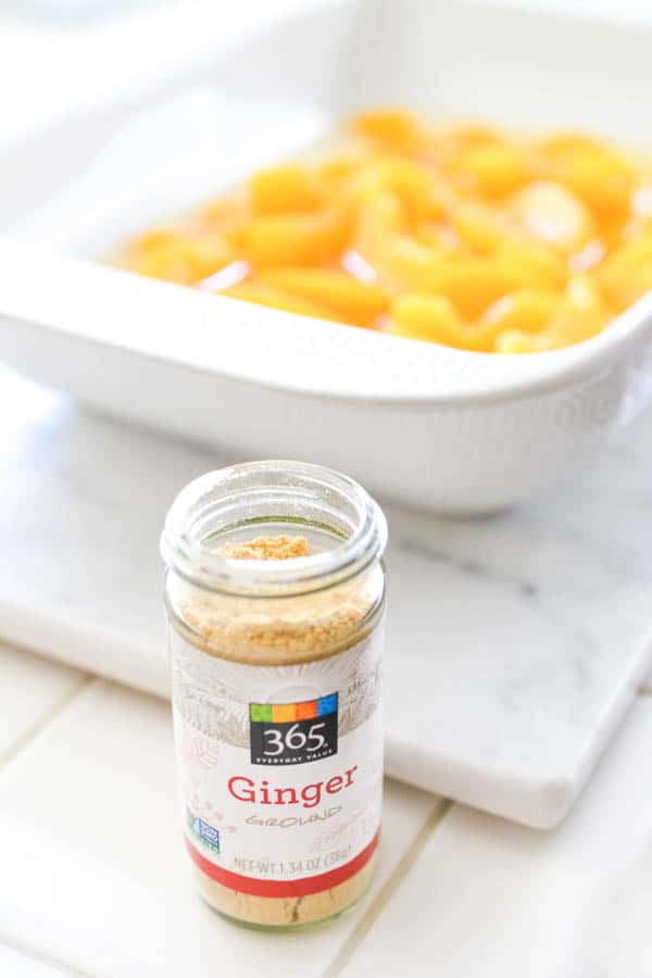 Close up of a ginger spice jar in front of dump cake in a pan.