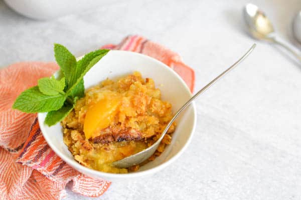 Serving of peach dump cake in a small bowl.