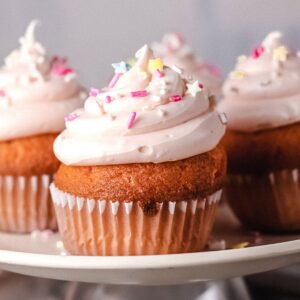 Close up of pink frosted cupcakes made with rosé wine topped with sprinkles on a plate.
