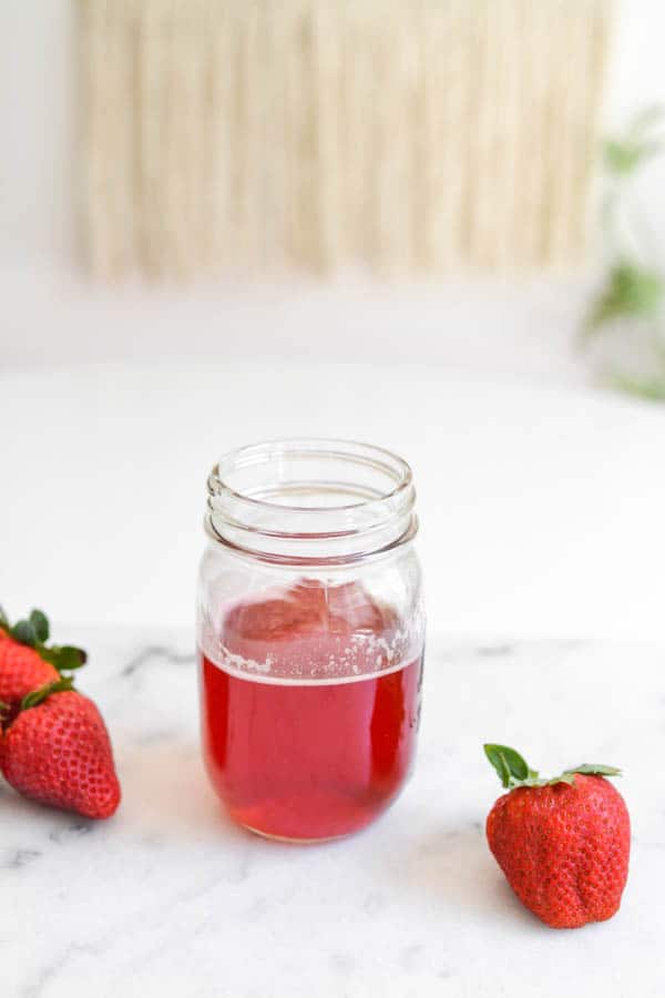Strawberry simple syrup in mason jar on a table. 