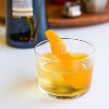 A close up of a glass of fortified wine with a orange peel garnish.