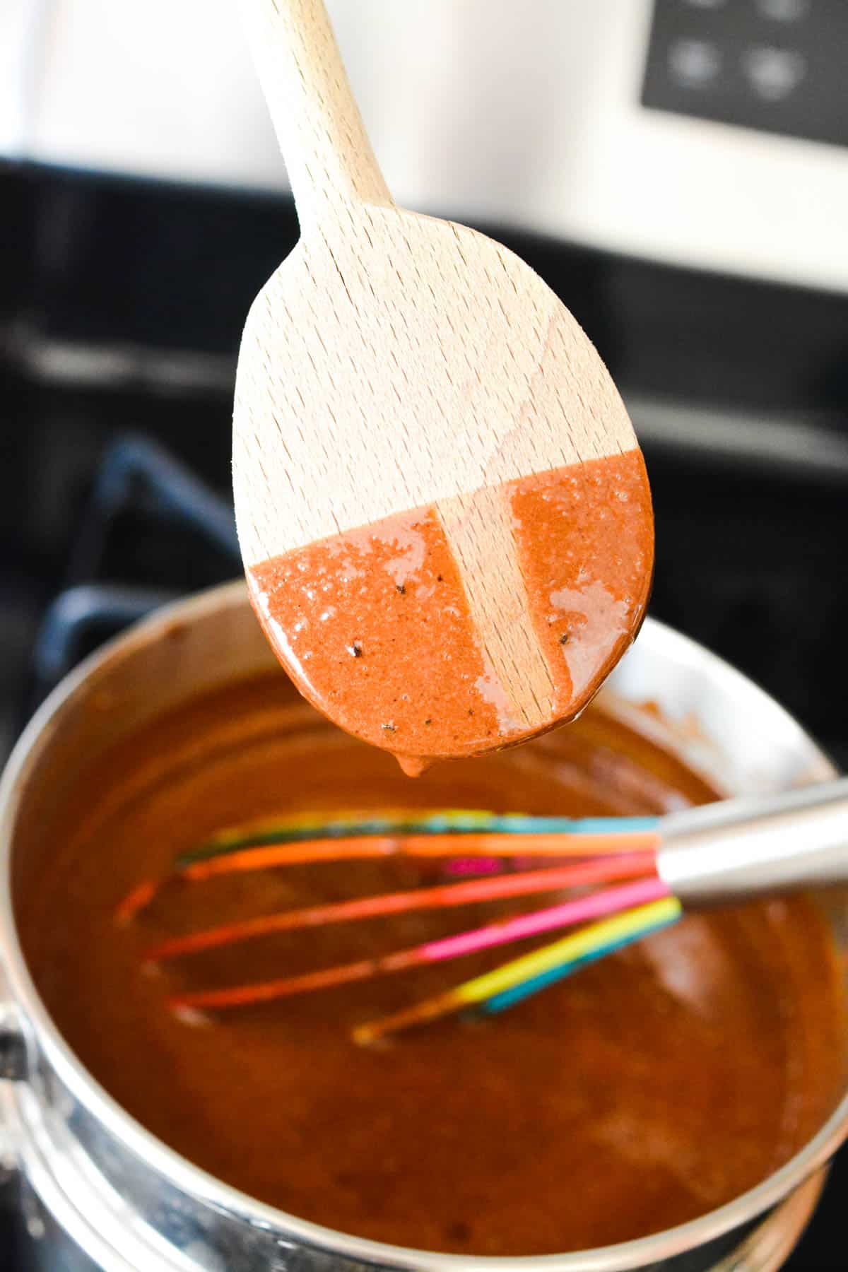A wooden spoon with a chocolate liquid on it with a stripe missing to test consistency.