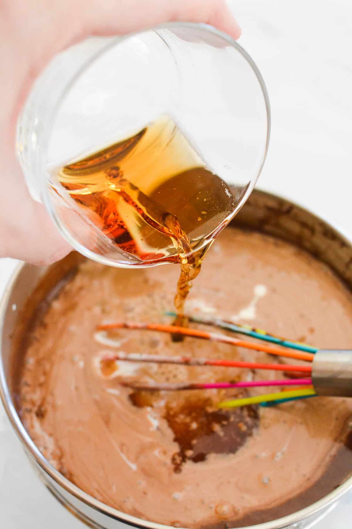 Adding beer to melted chocolate in a saucepan.
