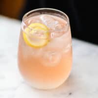 Rose Lemonade Spritzer in glass with a lemon twirl.