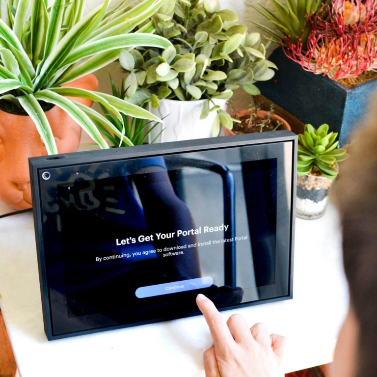 Kid setting up the Facebook Portal on a table with plants.
